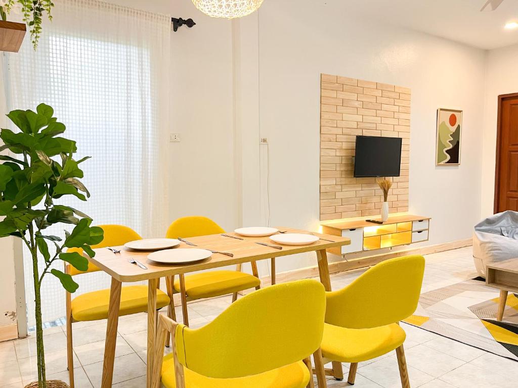 Ban Thalat Choeng ThaleH&Q 1BR Cozy House, Bangtao Beach的一间带桌子和黄色椅子的用餐室