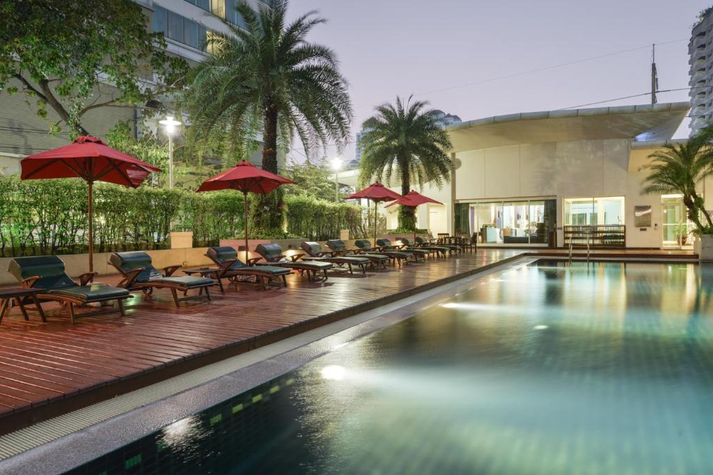 曼谷素坤逸通罗中心站酒店的一个带椅子和遮阳伞的游泳池