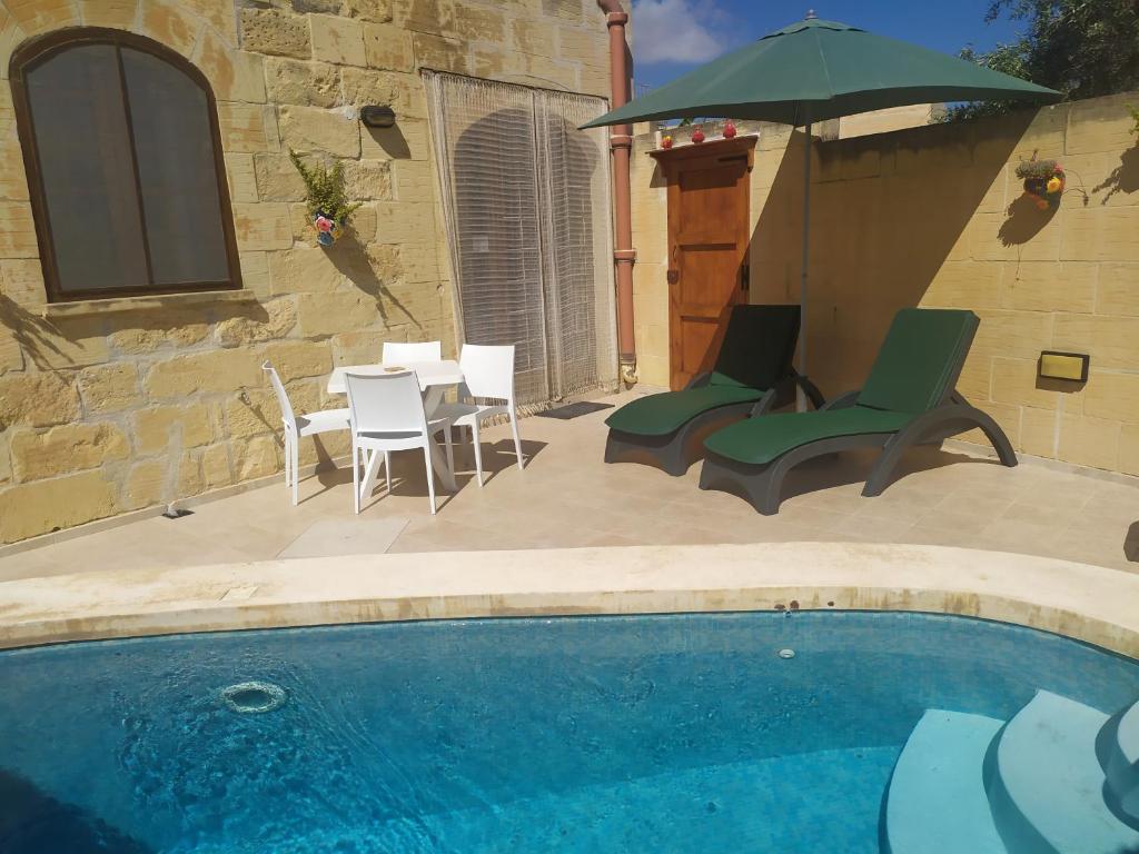 萨奈特Gozo Rustic Farmhouse with stunning views and swimming pool的一个带椅子和桌子的游泳池以及一把遮阳伞