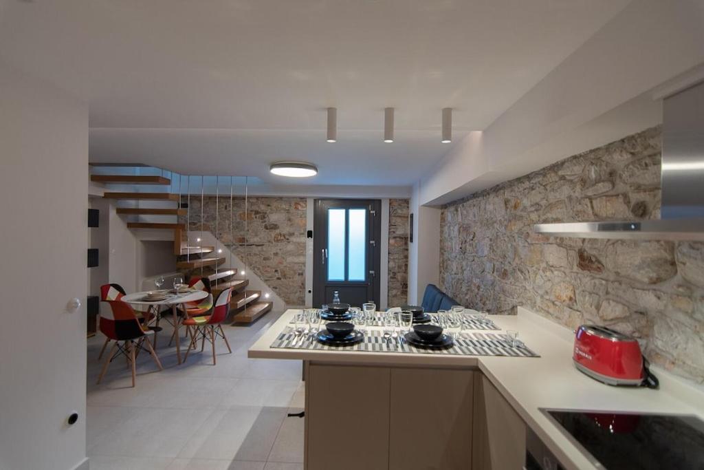 萨摩斯Villa Samos - Renovated stone villa with private pool- 2 min from the sea!的一间厨房和带石墙的用餐室
