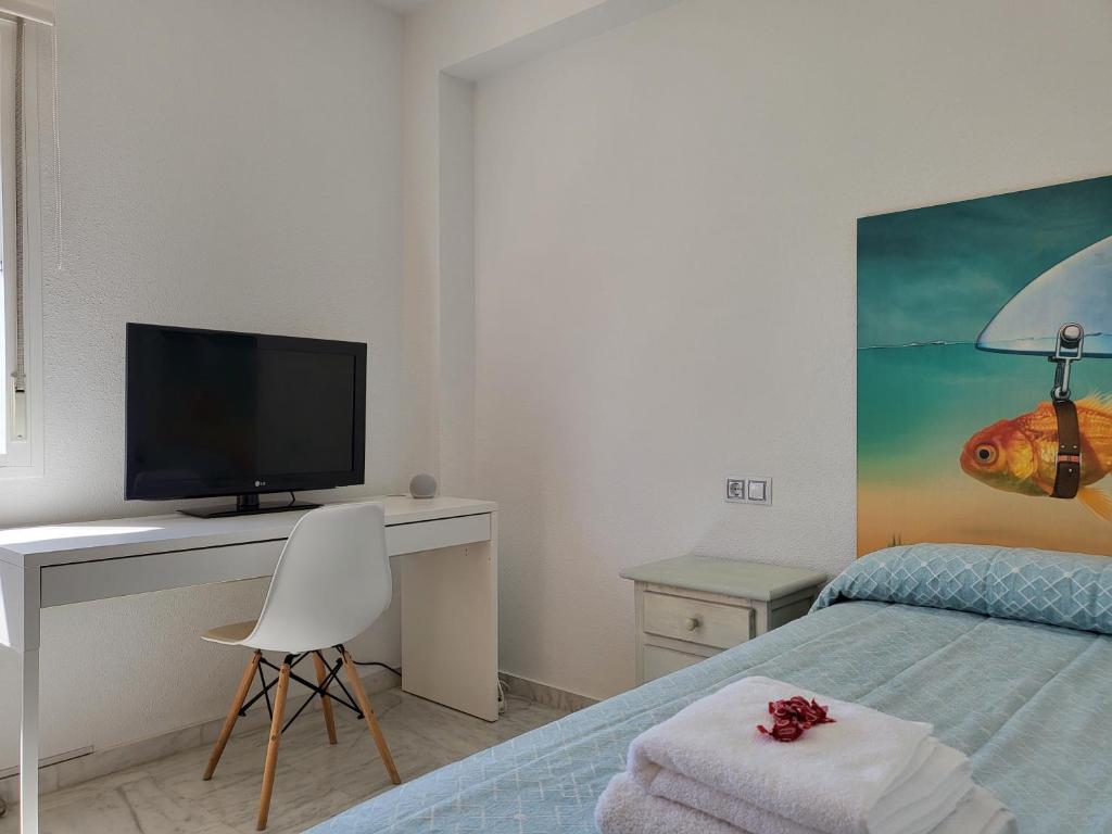 埃尔波提尔Adosado de lujo en El Portil Playa y Golf的一间卧室配有一张床和一张书桌及电视