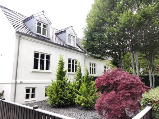 海宁Værelser i midtbyen的前面有树木和植物的白色房子