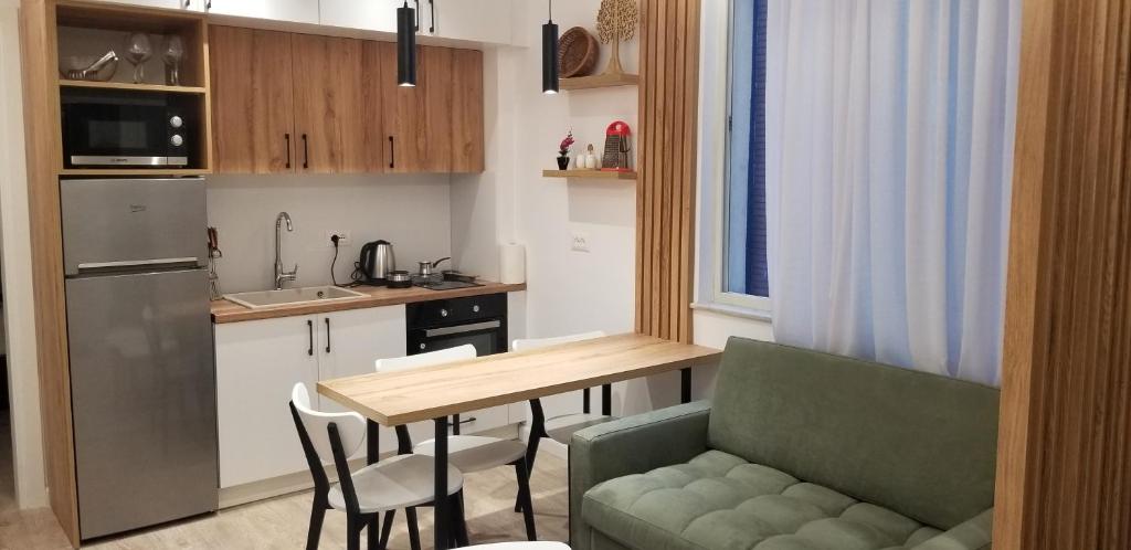 地拉那2A New Bazaar Apartment的一个带桌子和绿色沙发的小厨房