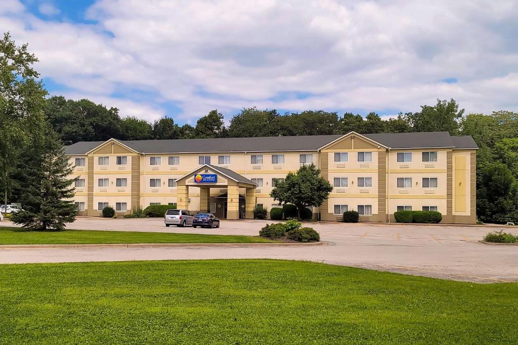 East MolineComfort Inn & Suites East Moline near I-80的一座黄色的大建筑,前面有一辆汽车