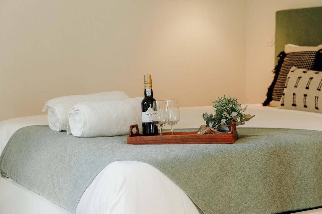 波尔图JARS Apartments - Casa do Bessa的床上有一瓶葡萄酒和两杯酒