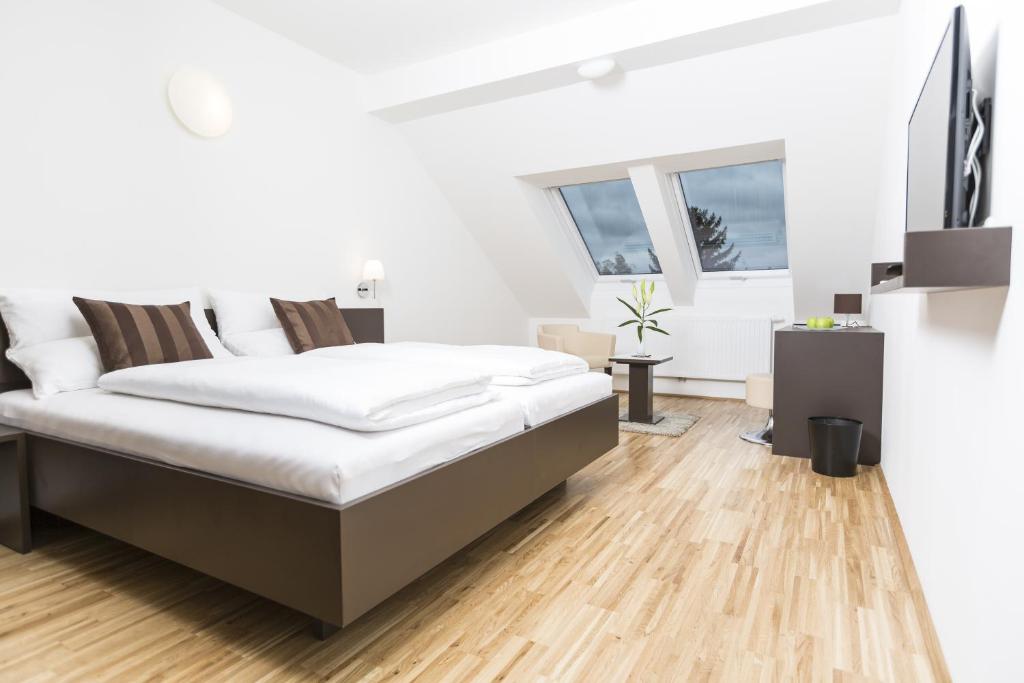 维也纳附近格拉斯多夫杰霍林格民宿的一间铺有木地板的白色卧室,配有一张床