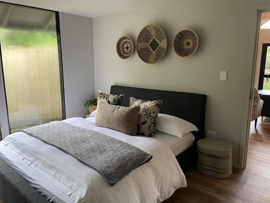 赫卢赫卢韦Tinswari Self-catering Chalet的卧室配有一张带枕头和盘子的床铺,墙上挂有枕头。