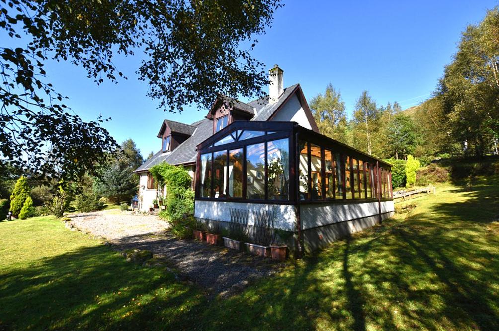 威廉堡Tarmachan Cottage - West Highland Getaway的院子里有很多窗户的房子