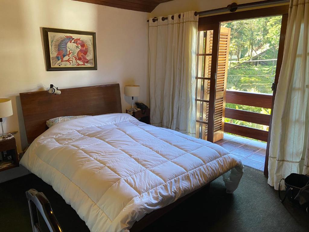 特雷索波利斯Casa encantadora na serra-Teresópolis的一间卧室设有一张大床和一个大窗户
