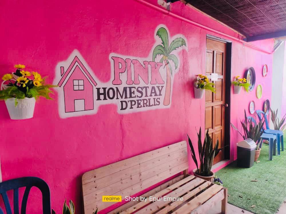 加央Pink Homestay D'Perlis的粉红色的房子,前面有长凳