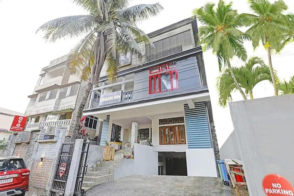 古瓦哈提Urban Inn Rukminigaon的前面有棕榈树的房子