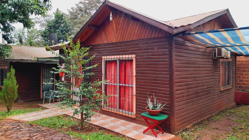 伊瓜苏港Voces De La Selva Misionera的一间设有红色门和绿色凳子的小房子