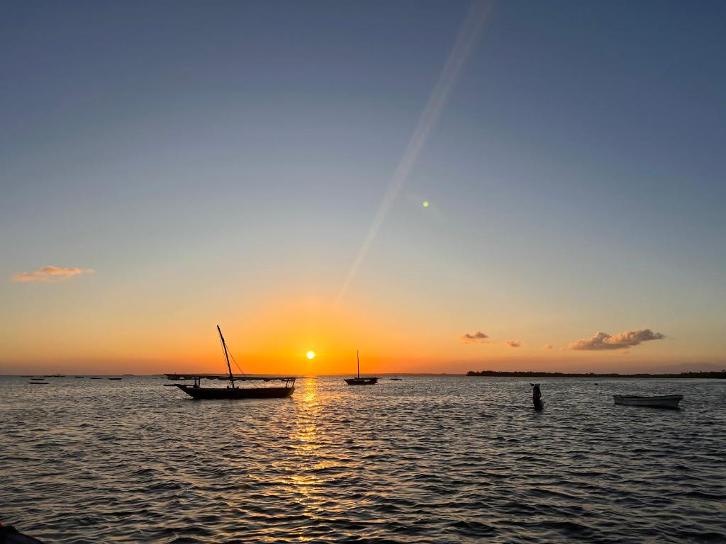 南威Sunrise Beach Nungwi的日落时分在水中的小船