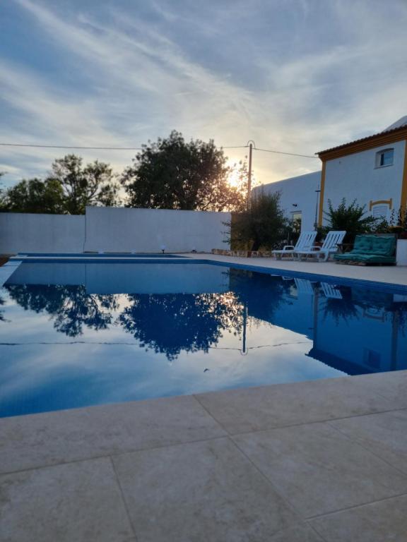 阿尔戈什Cosy Guest House - Villa das Alfarrobas的一个带围栏和椅子的游泳池,天空