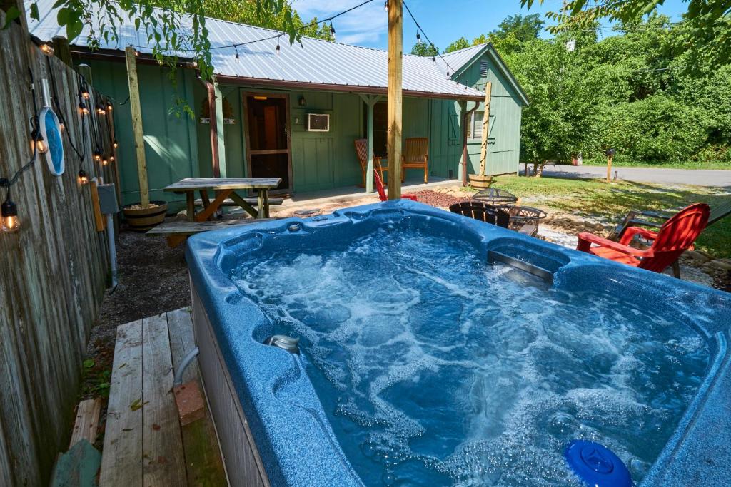 鸽子谷Steps from Downtown Pigeon Forge Parkway + Private Hottub and firepit - Wifi - Firefly Bungalows的一个带房子的院子内的蓝色热水浴缸