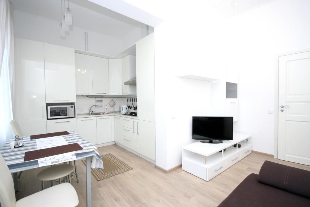 基辅基辅中心纯真家园公寓的一间带白色橱柜的厨房和一张带电视的书桌