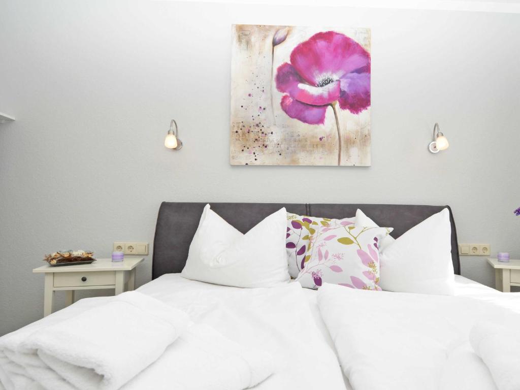 宾茨Wohnpark Stadt Hamburg - Apt. 22的卧室配有白色床,墙上挂有紫色花卉画