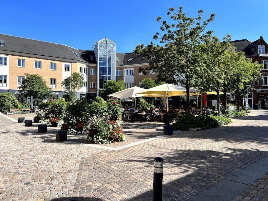 奥尔堡Apartment in the heart of Aalborg的庭院设有桌子、遮阳伞和树木