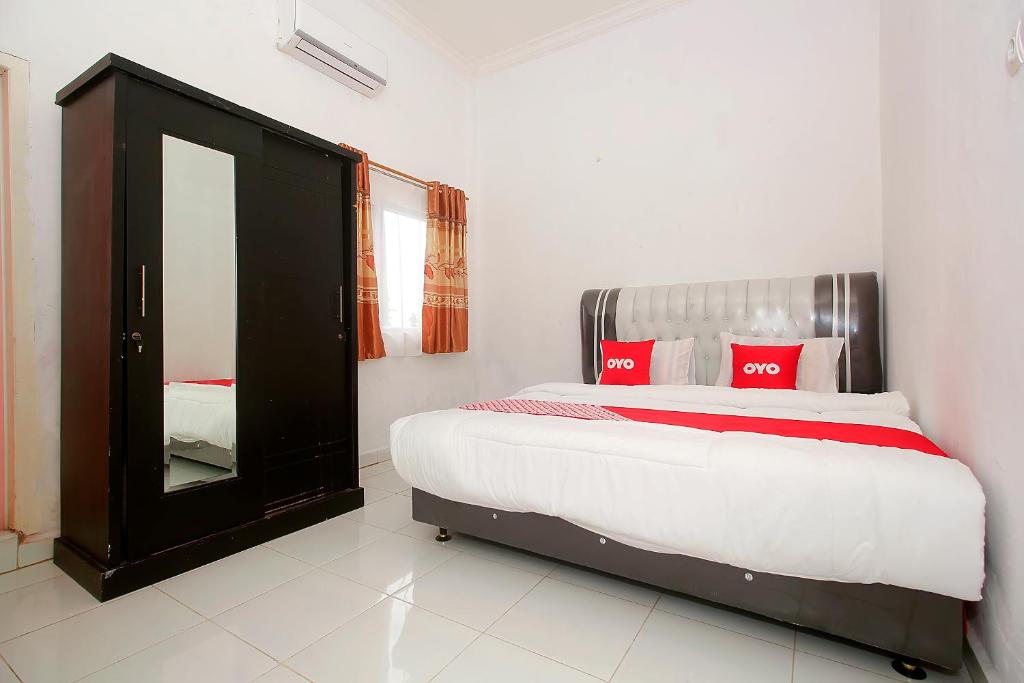 占碑市OYO 1847 Jasmine Kost Syariah的一间卧室配有一张带红色枕头和镜子的床