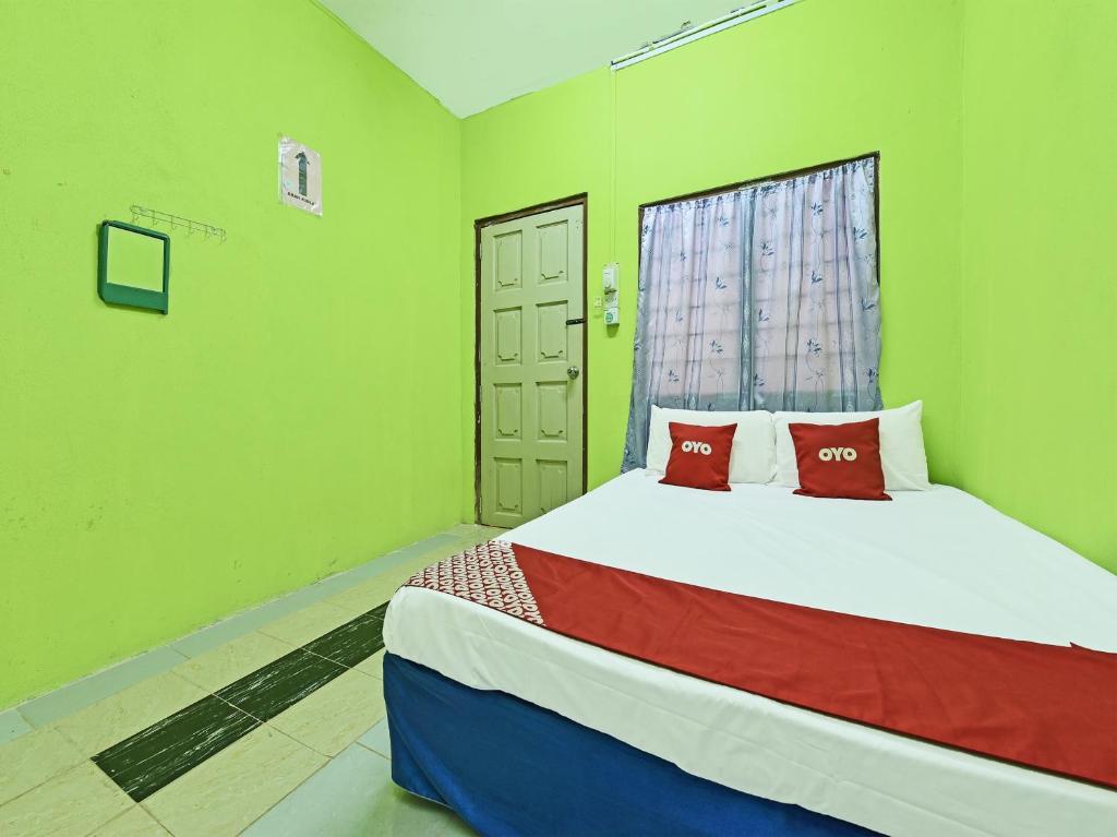 哥打巴鲁OYO 90454 Haza Harmoni Guesthouse的一间卧室设有一张带绿色墙壁和窗户的床。