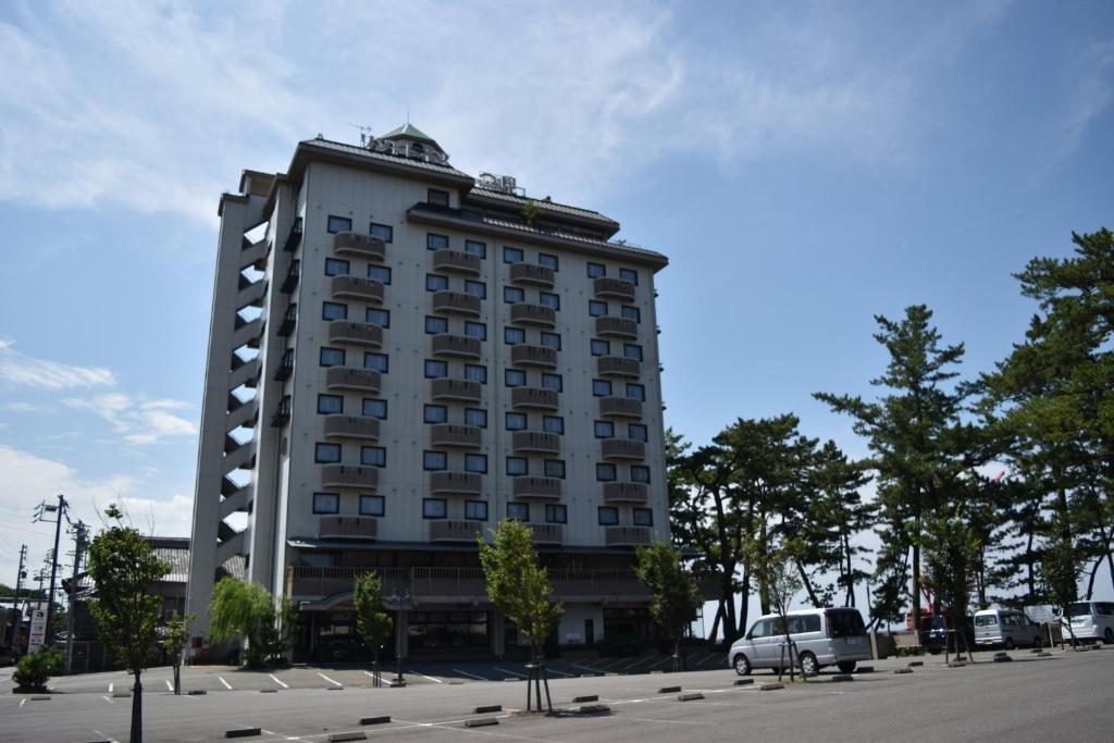 伊势市Hotel Castle Inn Ise Meotoiwa的一座高大的建筑,前面有一辆汽车