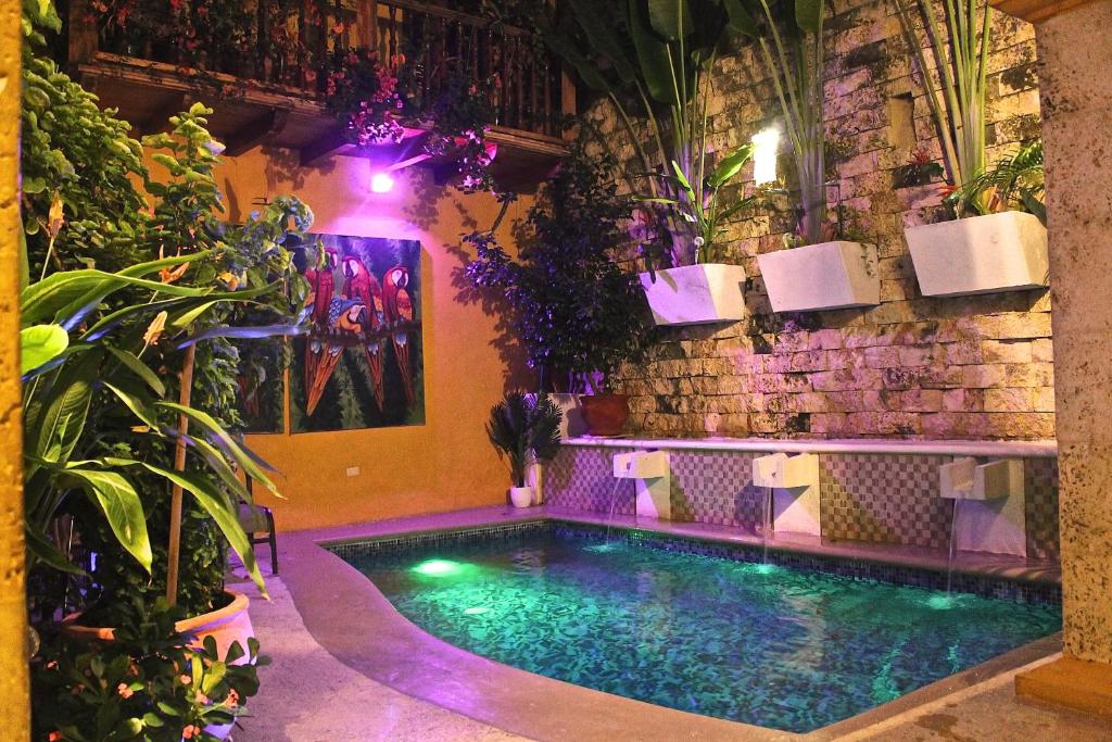 卡塔赫纳格罗里亚精品酒店的一座游泳池,位于砖墙前,种植了植物