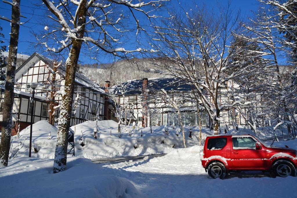 白马村Hotel Sejour Mint in Hakuba的停在雪覆盖的院子中的红色山 ⁇ 