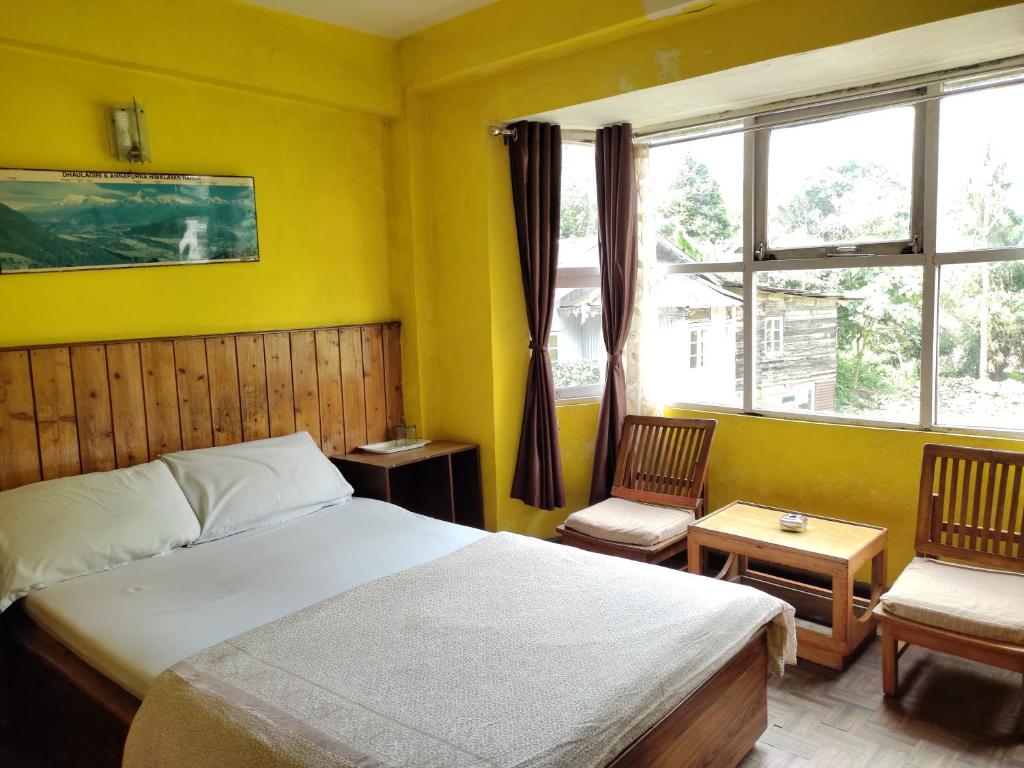 大吉岭Hotel Mhelung的一间卧室配有一张床、两把椅子和一个窗户