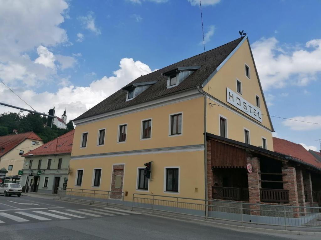 VojnikHostel Vojnik的街道上一座黄色建筑,屋顶黑色