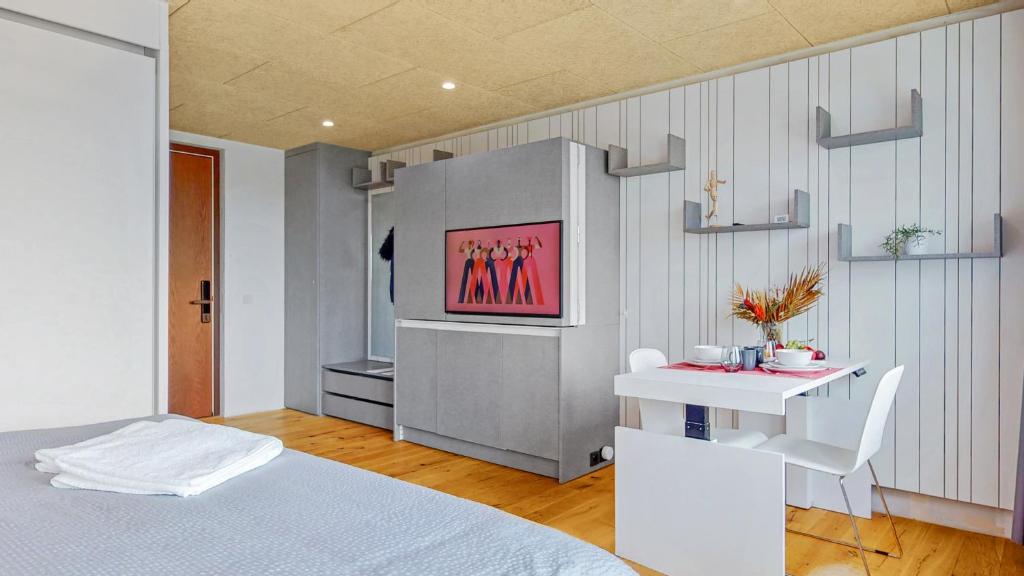 伯尔尼Evi's Home Hotel & Apartments的一间卧室配有一张床,墙上配有电视