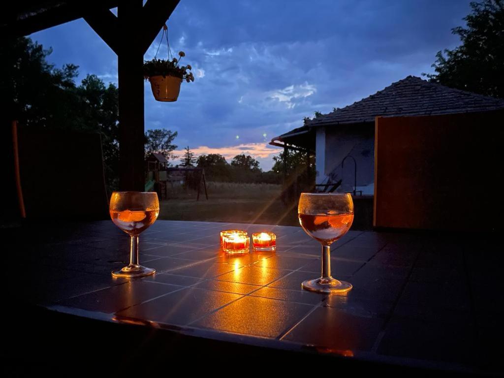 波罗斯洛Favorite Vendégház的两杯酒杯坐在带蜡烛的桌子上