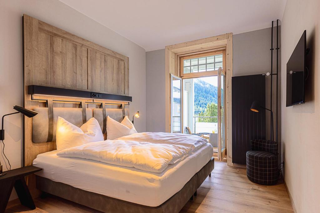 达沃斯ALPINE INN Davos的一间卧室设有一张大床和一个大窗户
