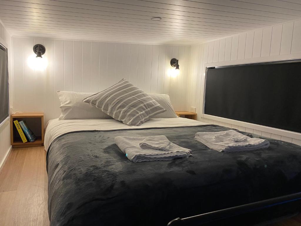 South BrunyAdina Tiny House Bruny Island的一间卧室配有一张大床和两条毛巾