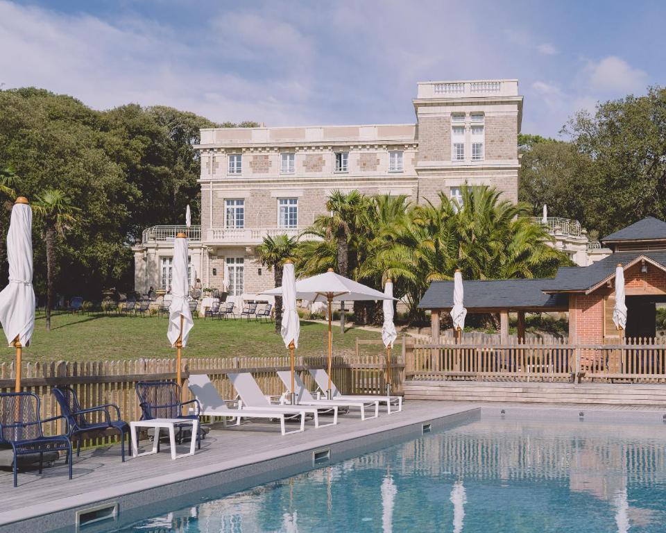 诺亚芒提亚Villa Arthus-Bertrand的大楼前的带椅子和遮阳伞的游泳池