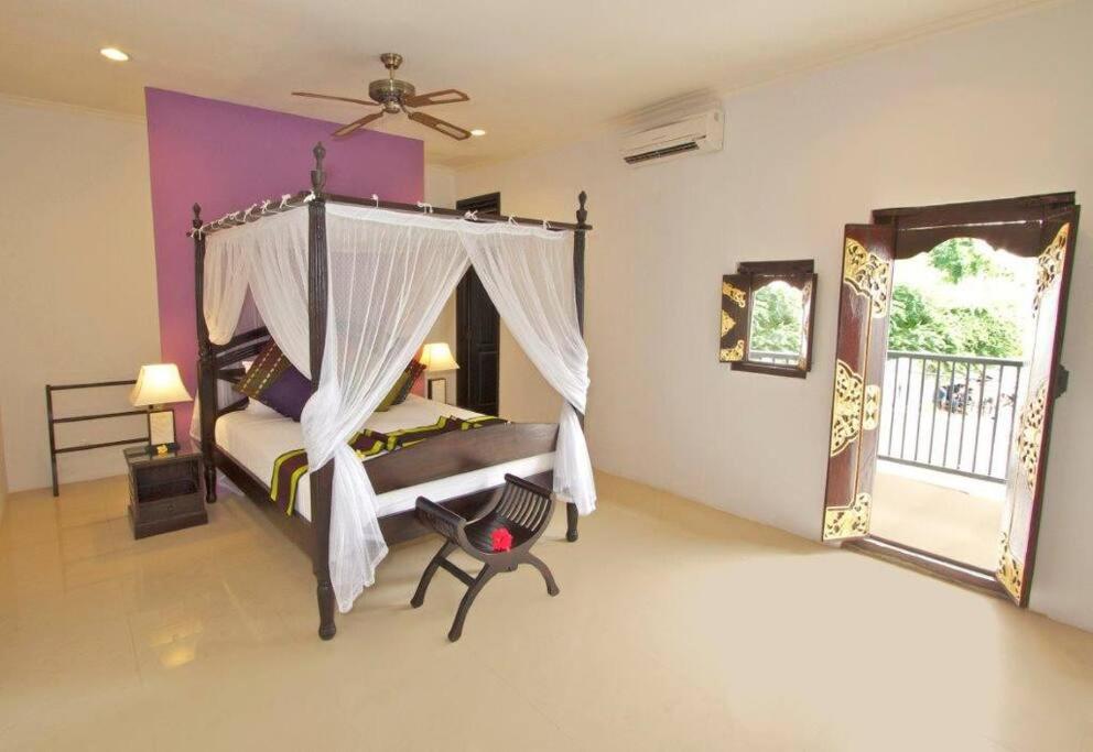 库塔5 Bedroom Holiday Villa - Kuta Regency B8的一间卧室设有一张天蓬床和一个阳台
