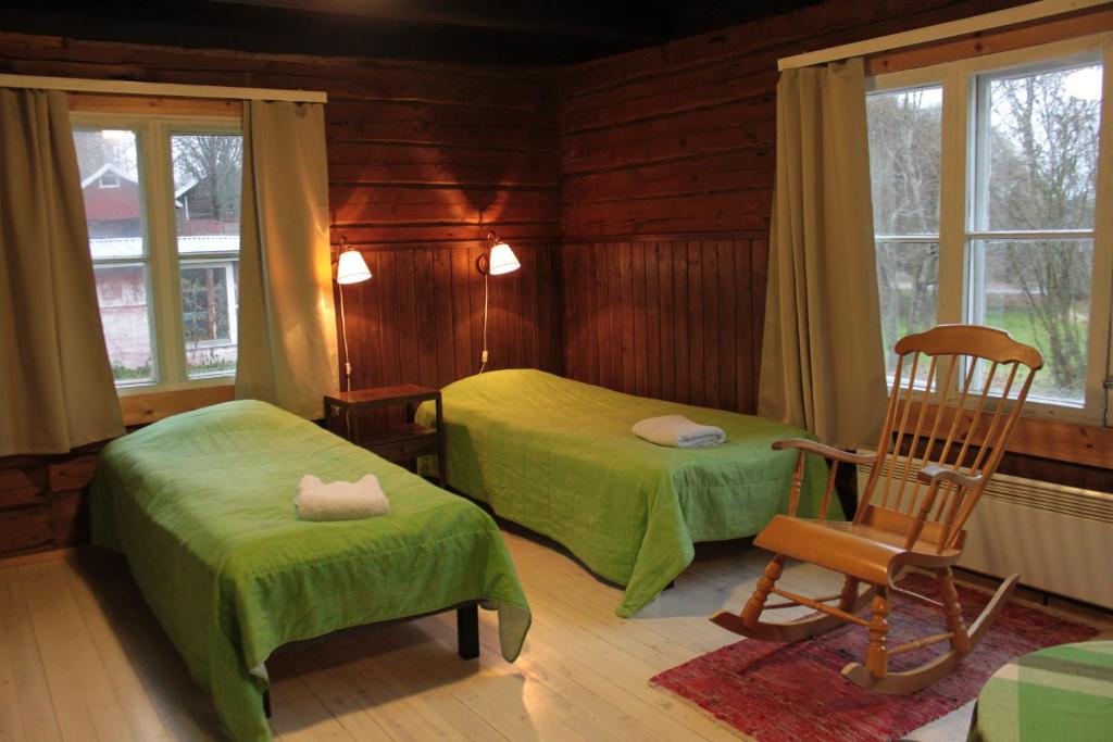 Ristiina卡尔塔诺罗顿酒店的一间卧室配有两张床和一把摇椅