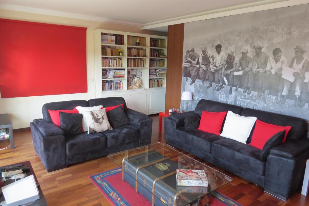 布拉加布拉加甜蜜的家旅舍的客厅设有两张黑色沙发和一堵红色的墙
