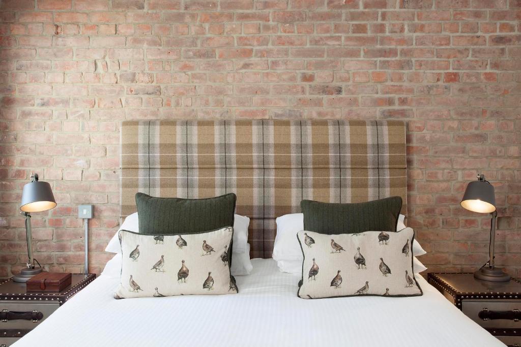 圣艾夫斯塘鹅旅馆的一张带两个枕头和砖墙的床
