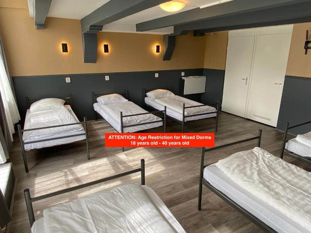 阿姆斯特丹Xplore Hostel Amsterdam的一间房间,有三张床和一个标志,上面写着租住房间移民费的报销