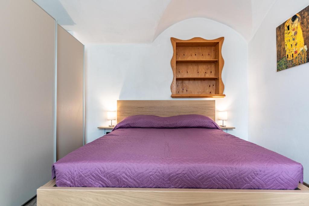 佩尔吉内瓦尔苏加纳Residenza Glicine的一间卧室配有一张带木制床头板的紫色床