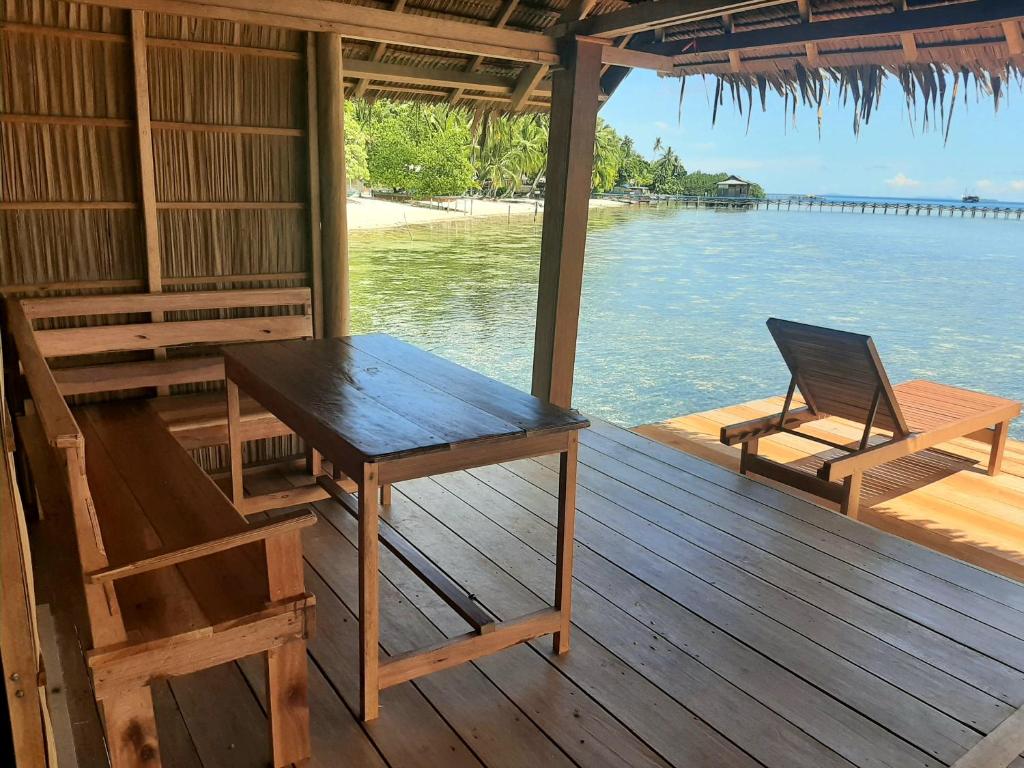 Pulau MansuarFrances Homestay - Raja Ampat的一张桌子和椅子,坐在甲板上,水面