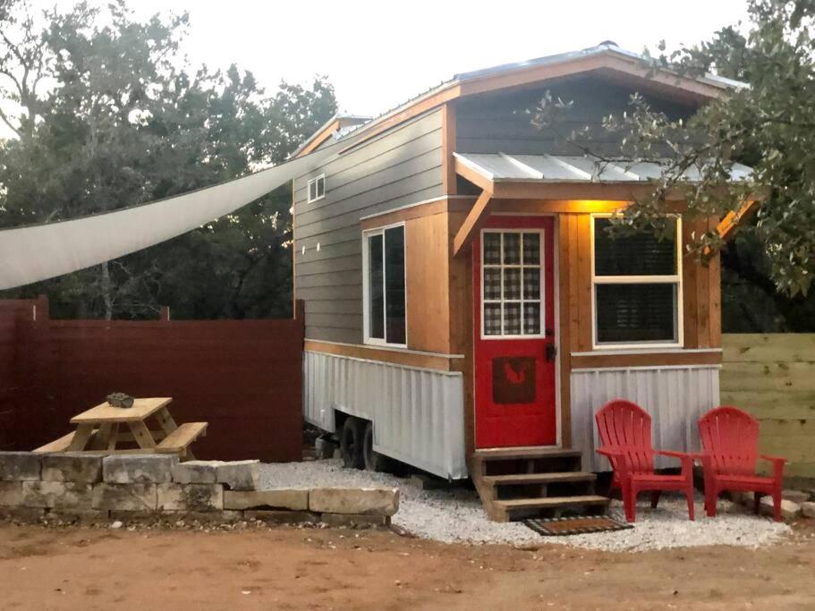 奥斯汀Fox Tiny Home - The Cabins at Rim Rock的一间小房子,有红色的门和两张红色椅子