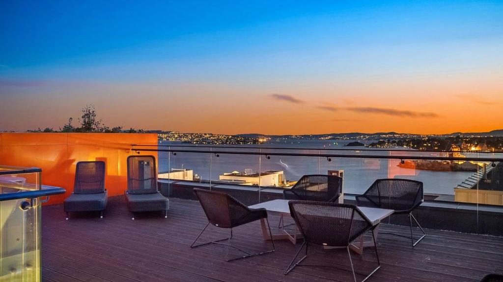 奥斯陆Exclusive apartment, sea view to Oslo fjord, located on water in Oslo center的阳台的甲板上配有桌椅