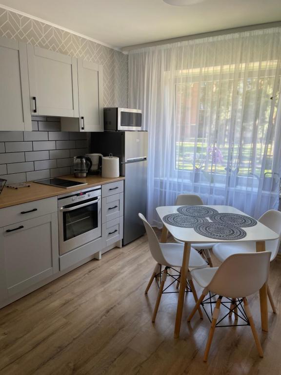 维萨吉纳斯Nice to stay的一间带桌椅的厨房和一间带白色橱柜的厨房