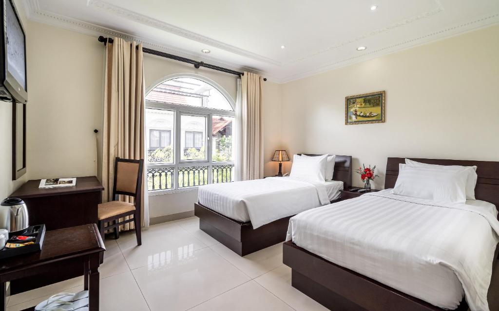 胡志明市La Bonita Hotel and Apartments的酒店客房设有两张床和窗户。