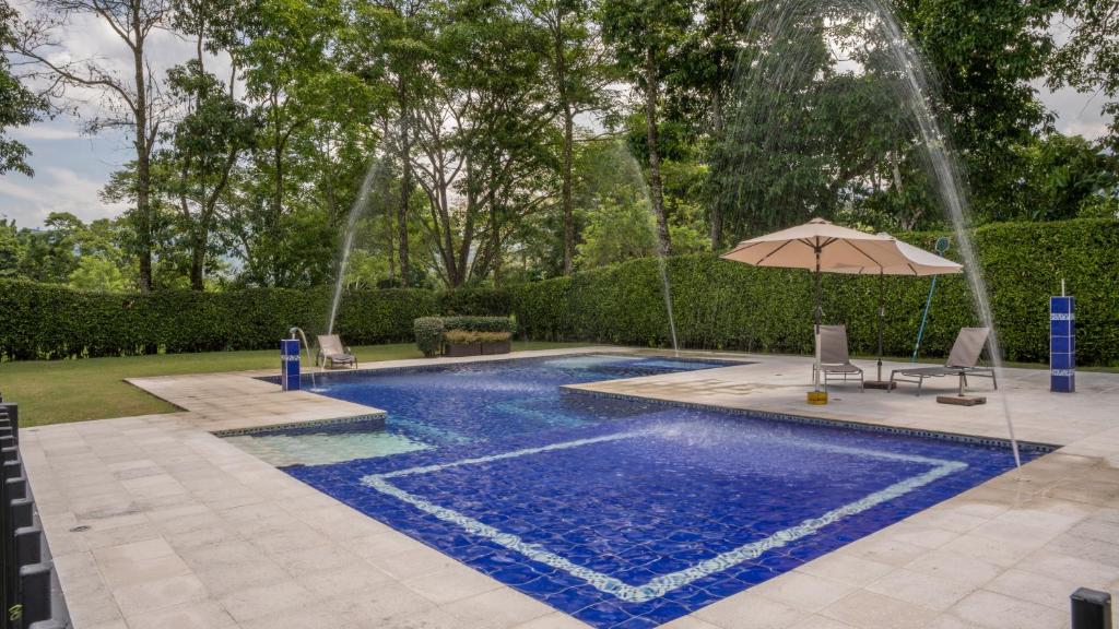佩雷拉Hotel Palo Grande CF Pereira的一个带遮阳伞和喷泉的游泳池