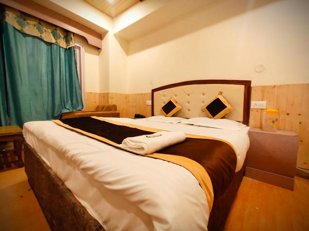 西姆拉Shorya Regency的一间卧室配有一张大床和两条毛巾