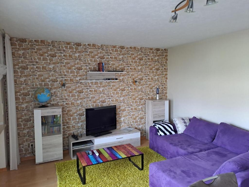 皮特林根Ferienwohnung Schleiten的客厅配有紫色沙发和砖墙