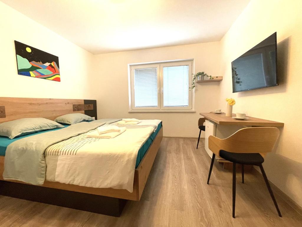 采尔克诺Apartments and rooms pri Bašlju的一间卧室配有一张床、一张书桌和一台电视