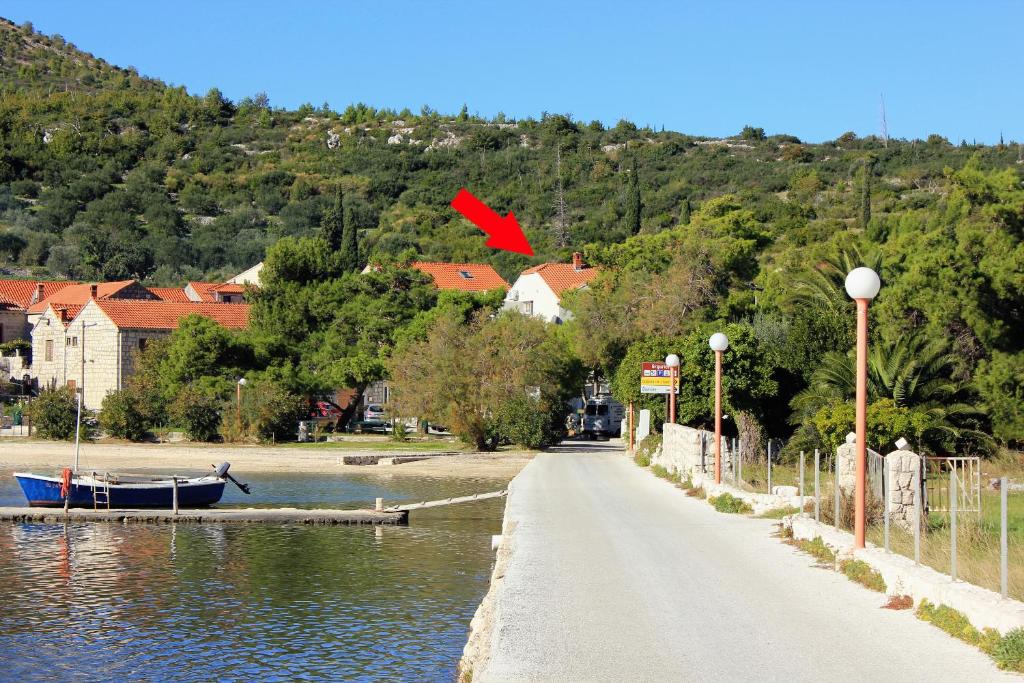 斯拉诺Apartments by the sea Slano, Dubrovnik - 8608的一条河边的道路,河上有一条船